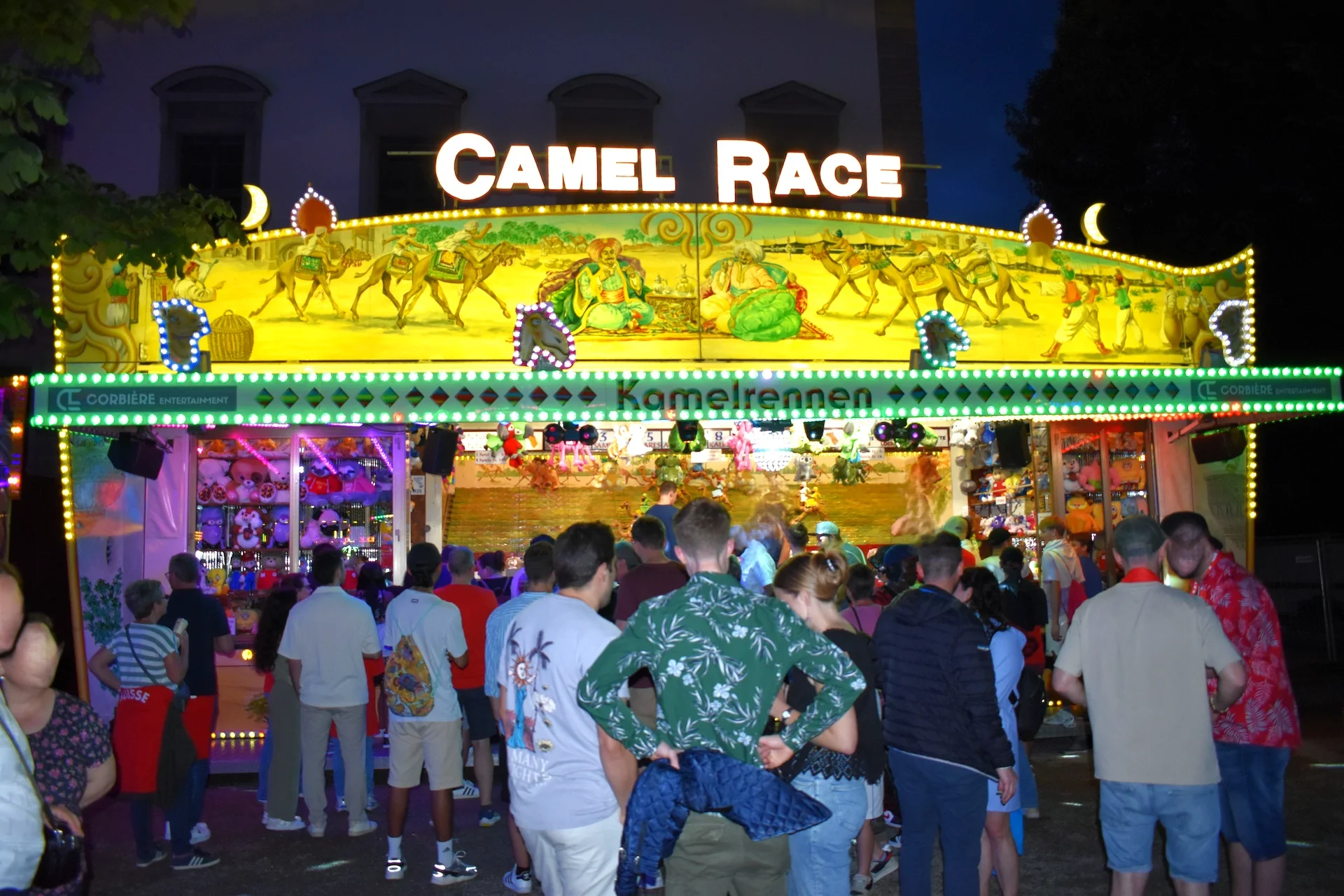 Camel Race Chilbi Stand bei Nacht, davor viele Menschen